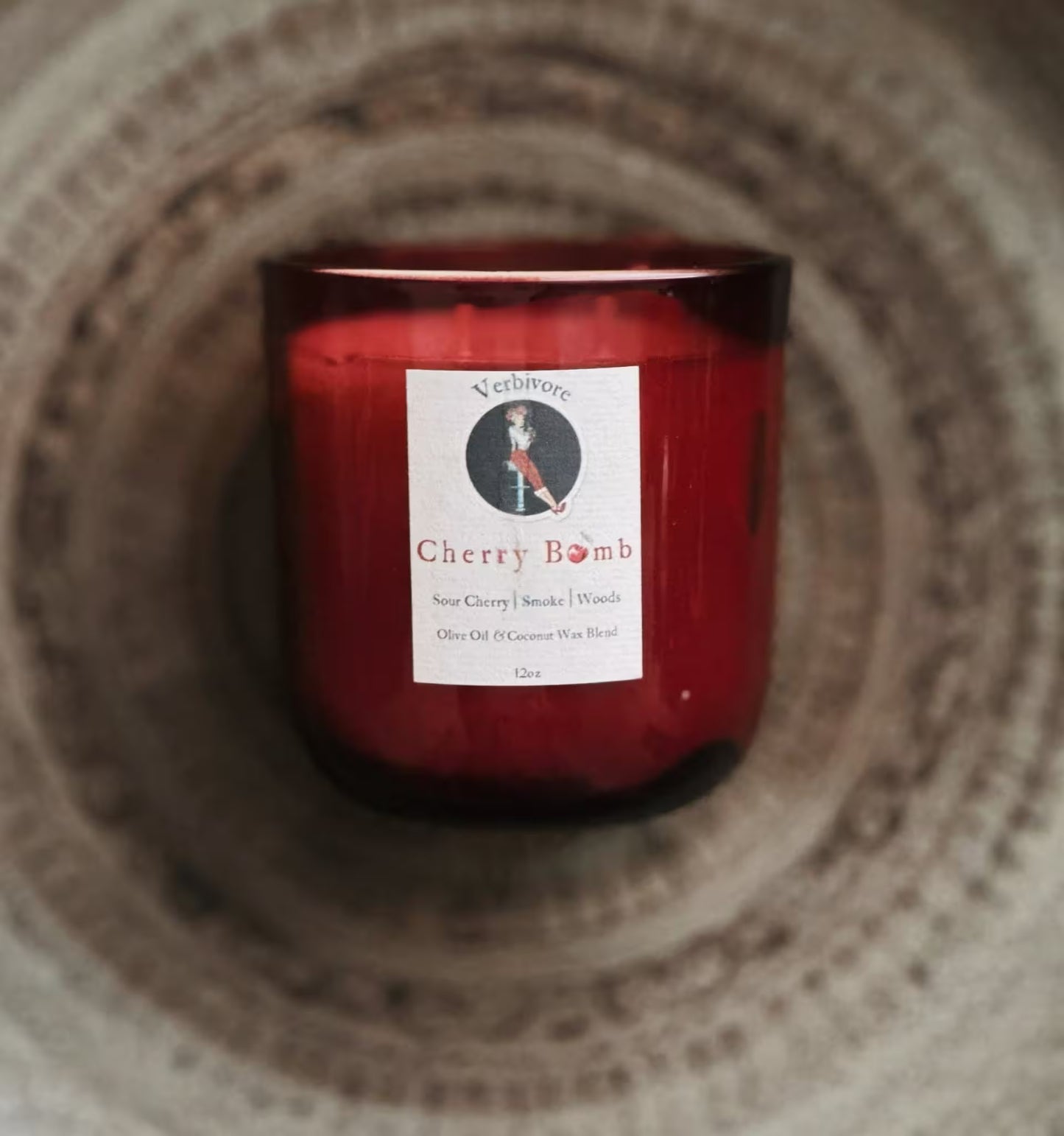 Red candle with a label on a textured surface