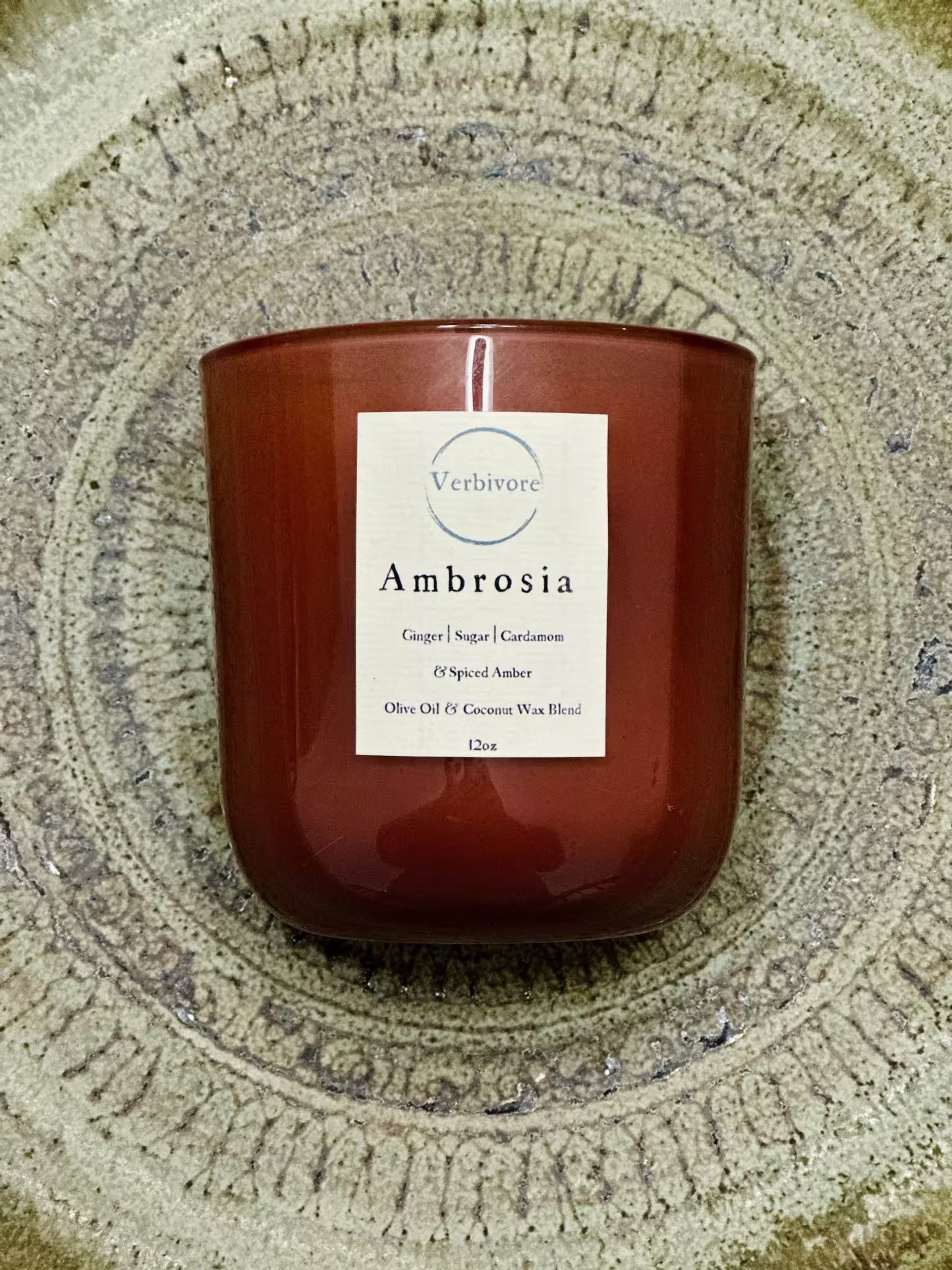 Red candle with a white label on a textured surface