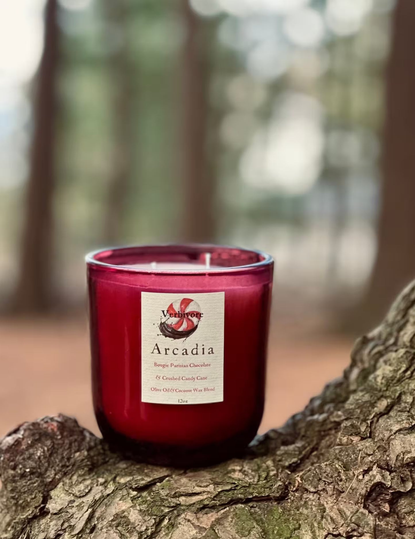 Red candle labeled 'Arcadia' on a tree stump with a forest background