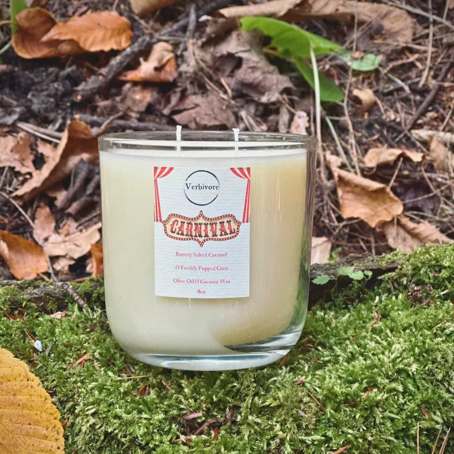 Candle with a label on a natural background of leaves and moss