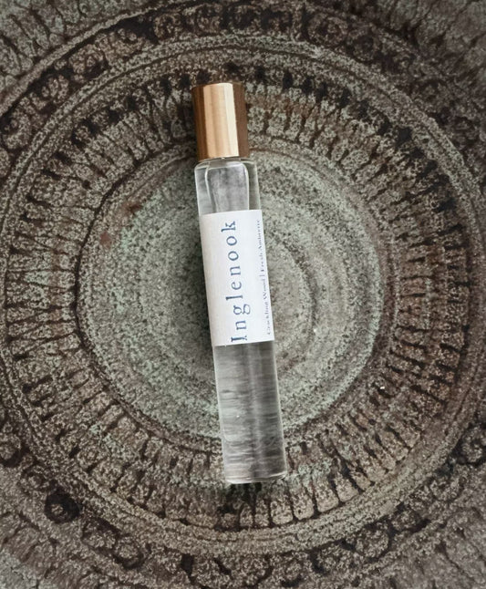 Small clear bottle with a gold cap on a textured stone surface, with the word 'Inglenook'.