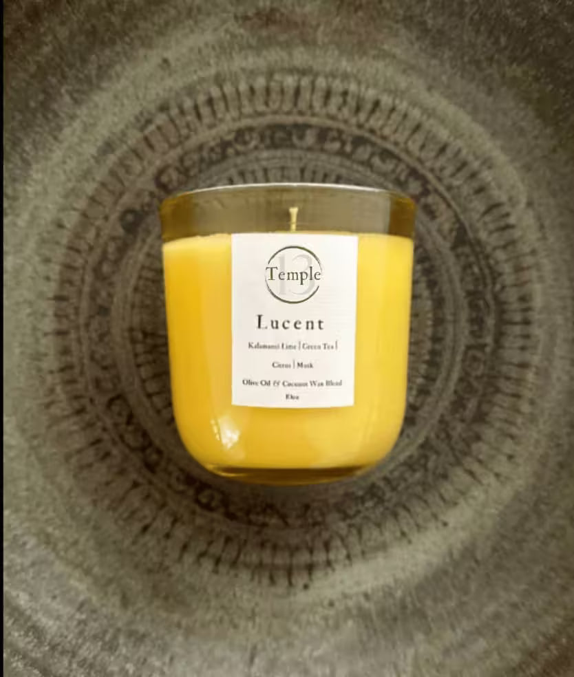 Yellow candle in a glass jar with a white label on a textured surface