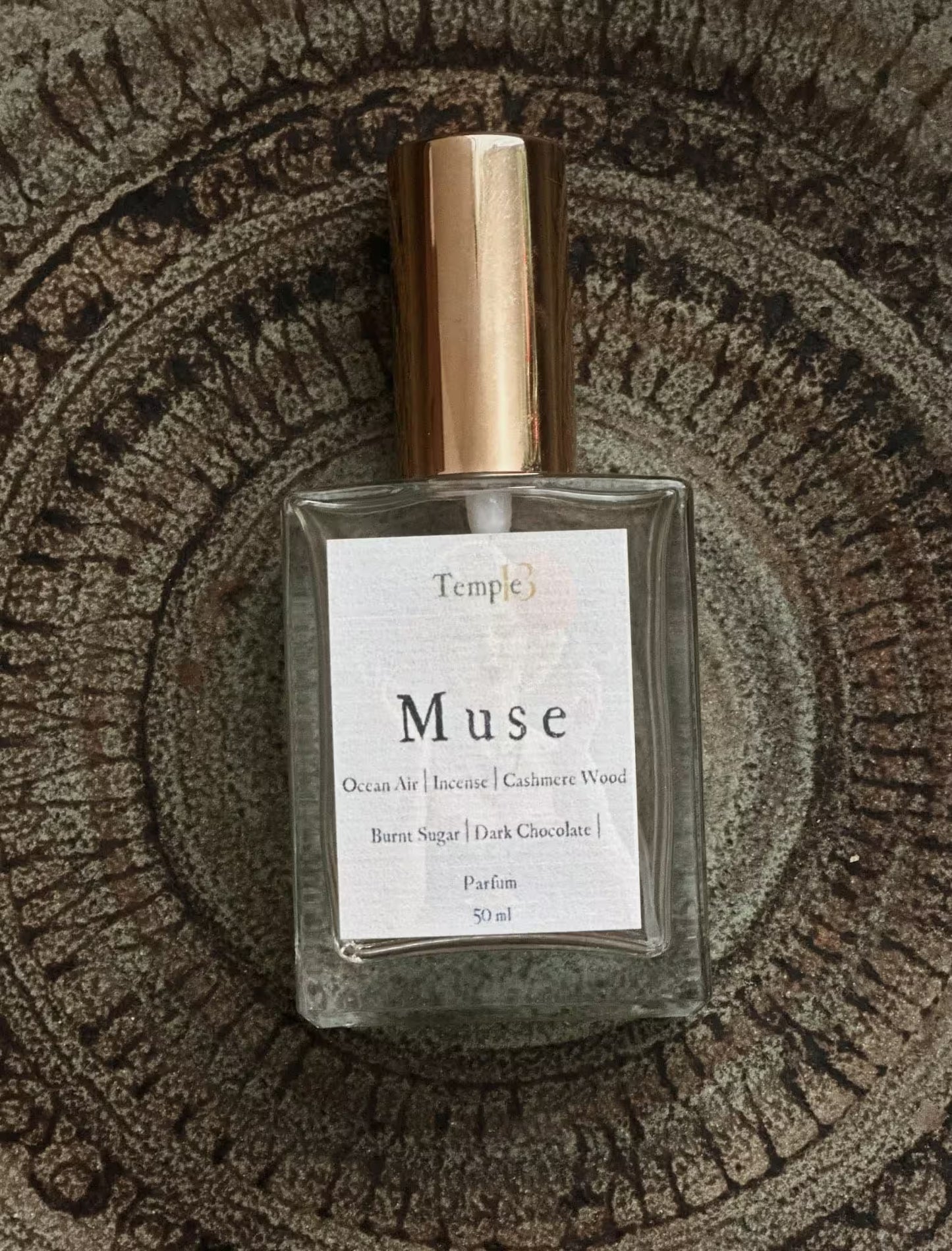 Perfume bottle labeled 'Muse' by Temple on a textured surface