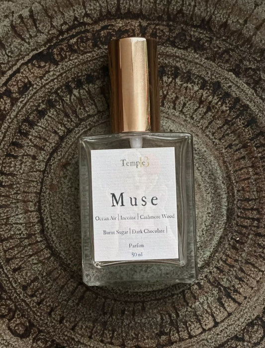 Perfume bottle labeled 'Muse' by Temple on a textured surface