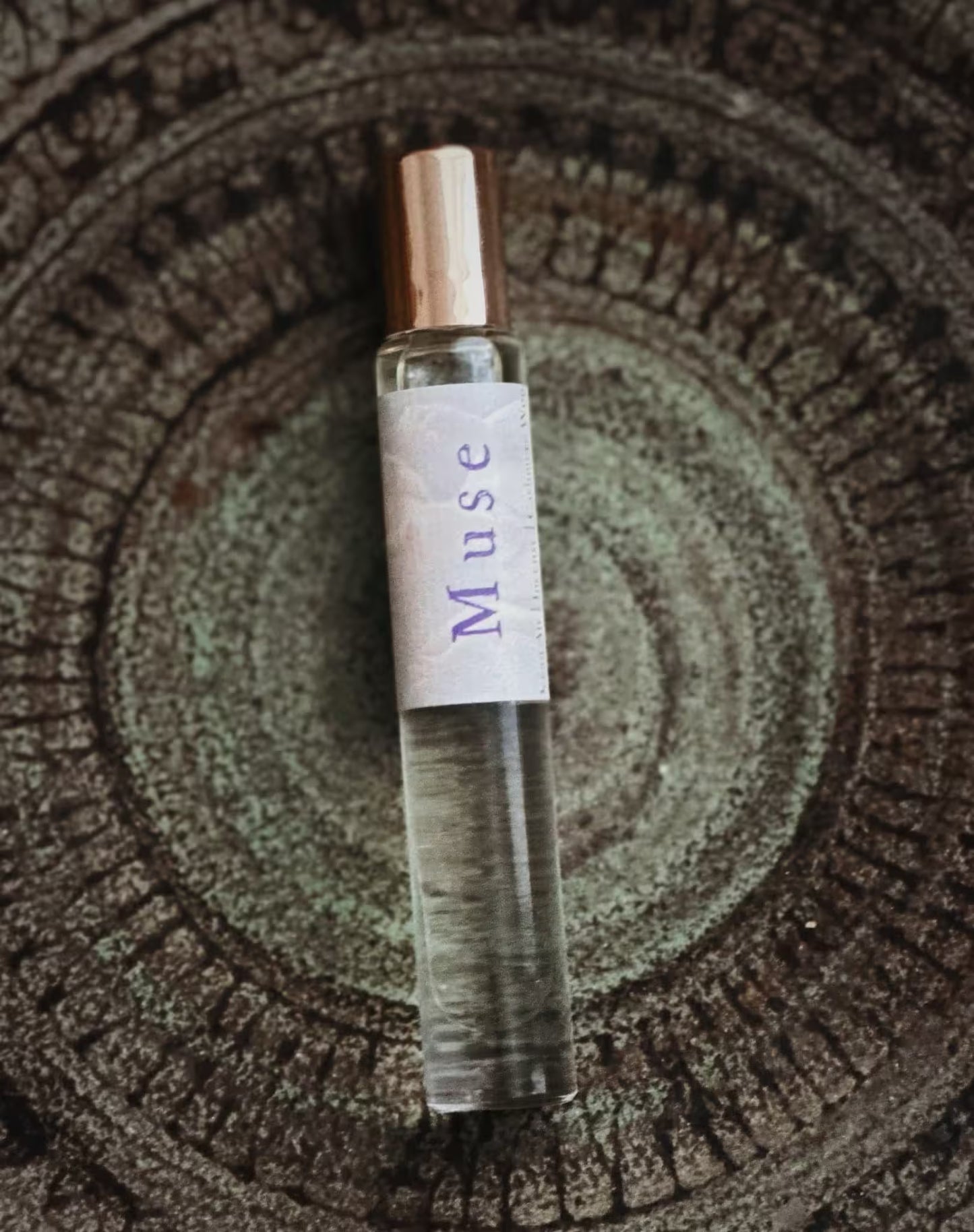 Small glass bottle labeled 'Muse' on a textured surface