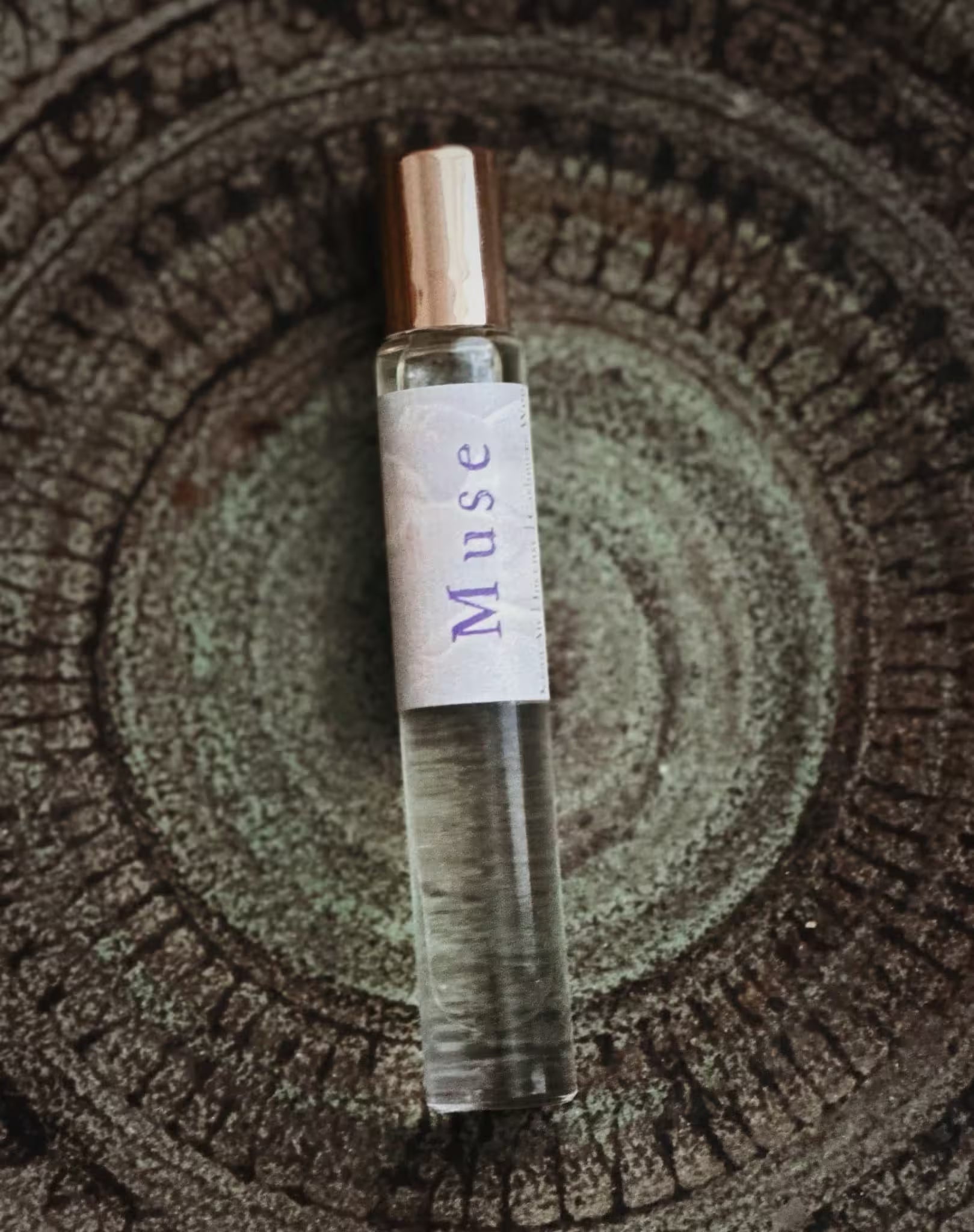 Small glass bottle labeled 'Muse' on a textured surface