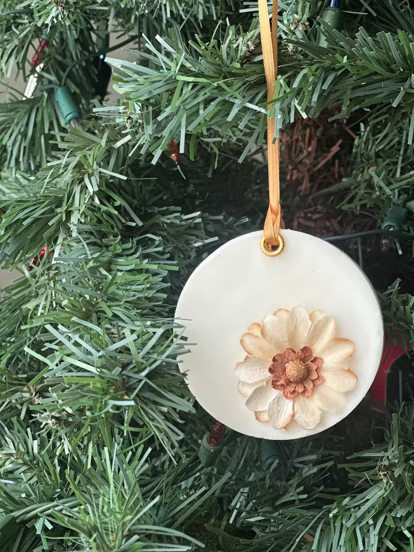 Decorative ornament with a floral design hanging on a Christmas tree.