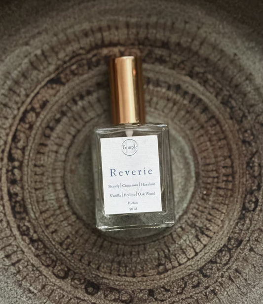 Perfume bottle labeled 'Reverie' by Temple on a textured surface