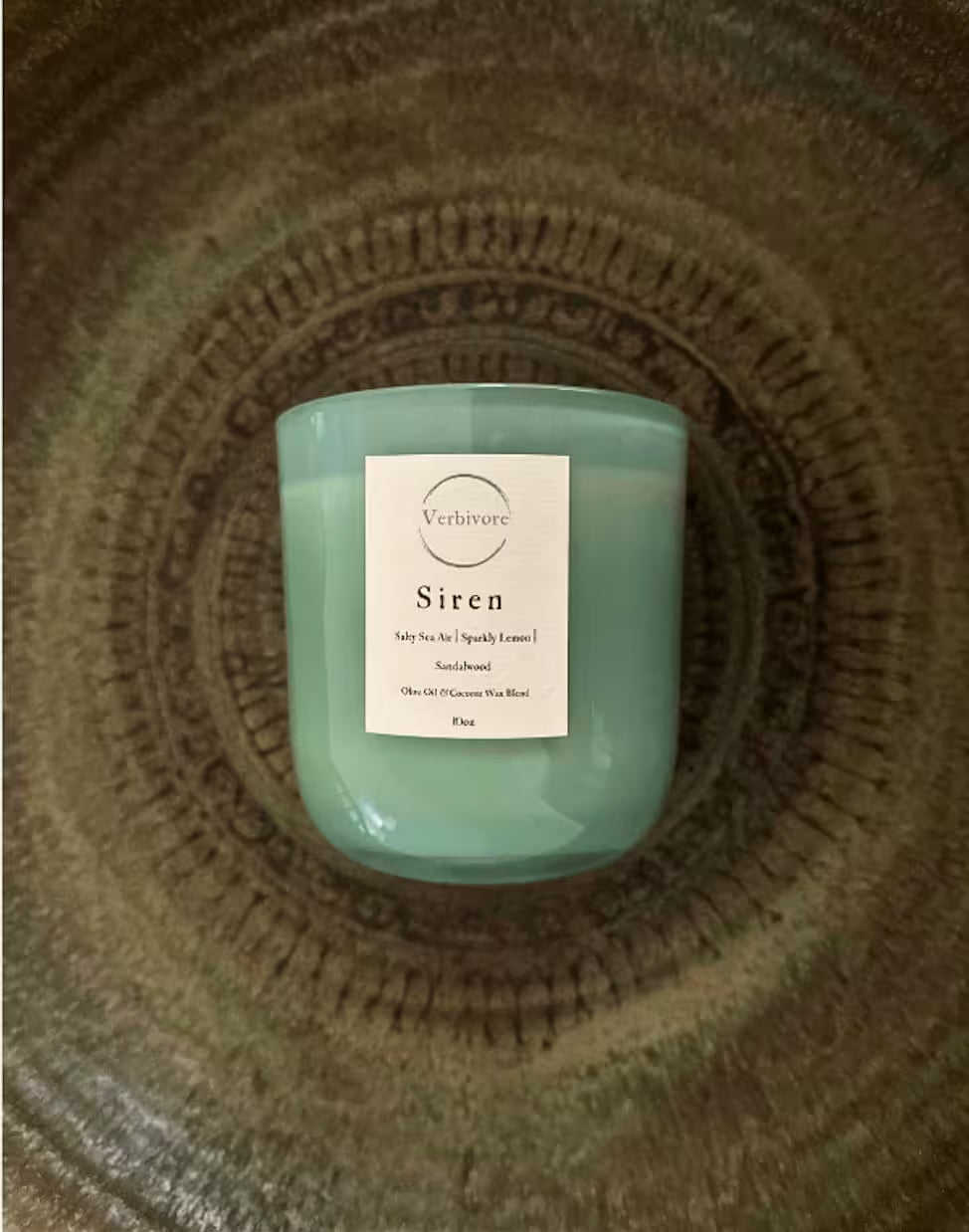 Green candle labeled 'Siren' on a textured surface